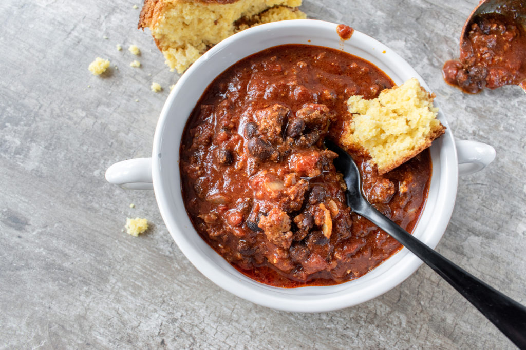 Bowl of chili with black beans and cornbread flat lay